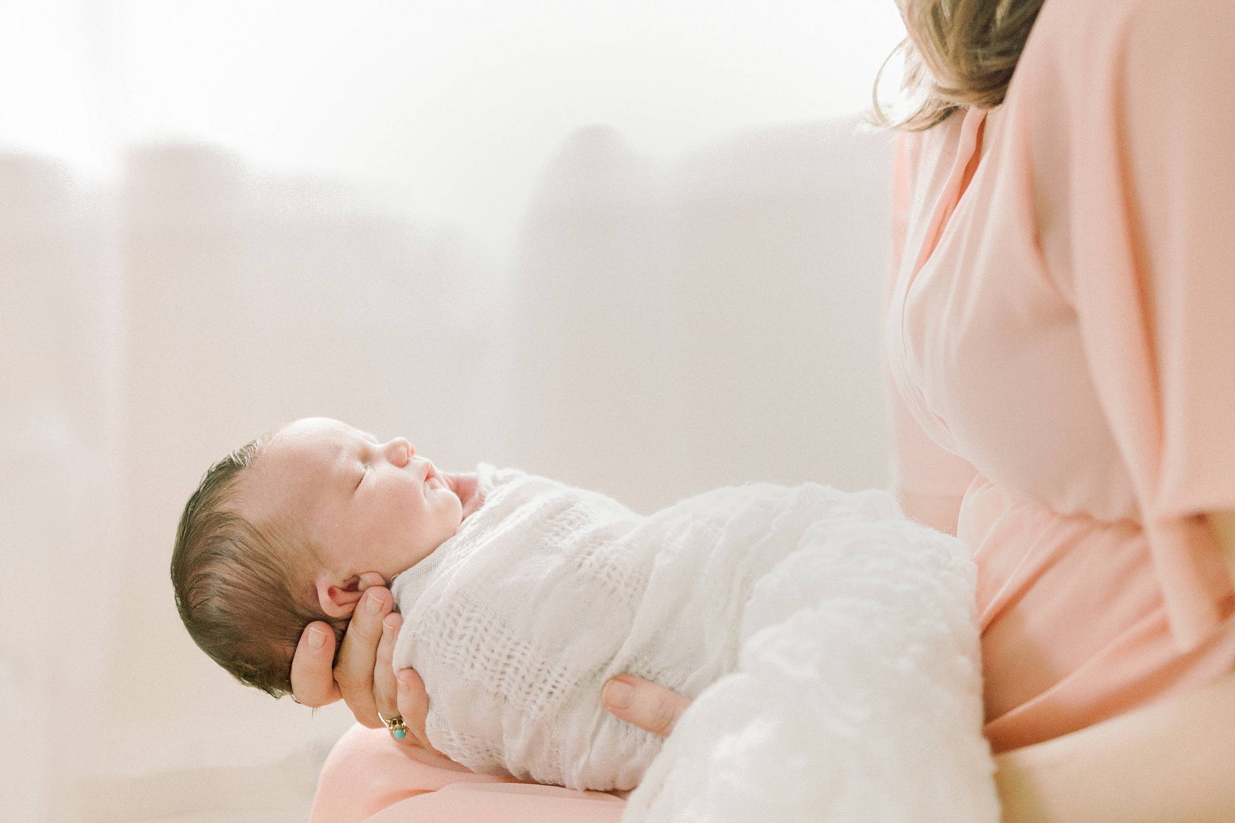 Swaddled newborn baby in mother's arms