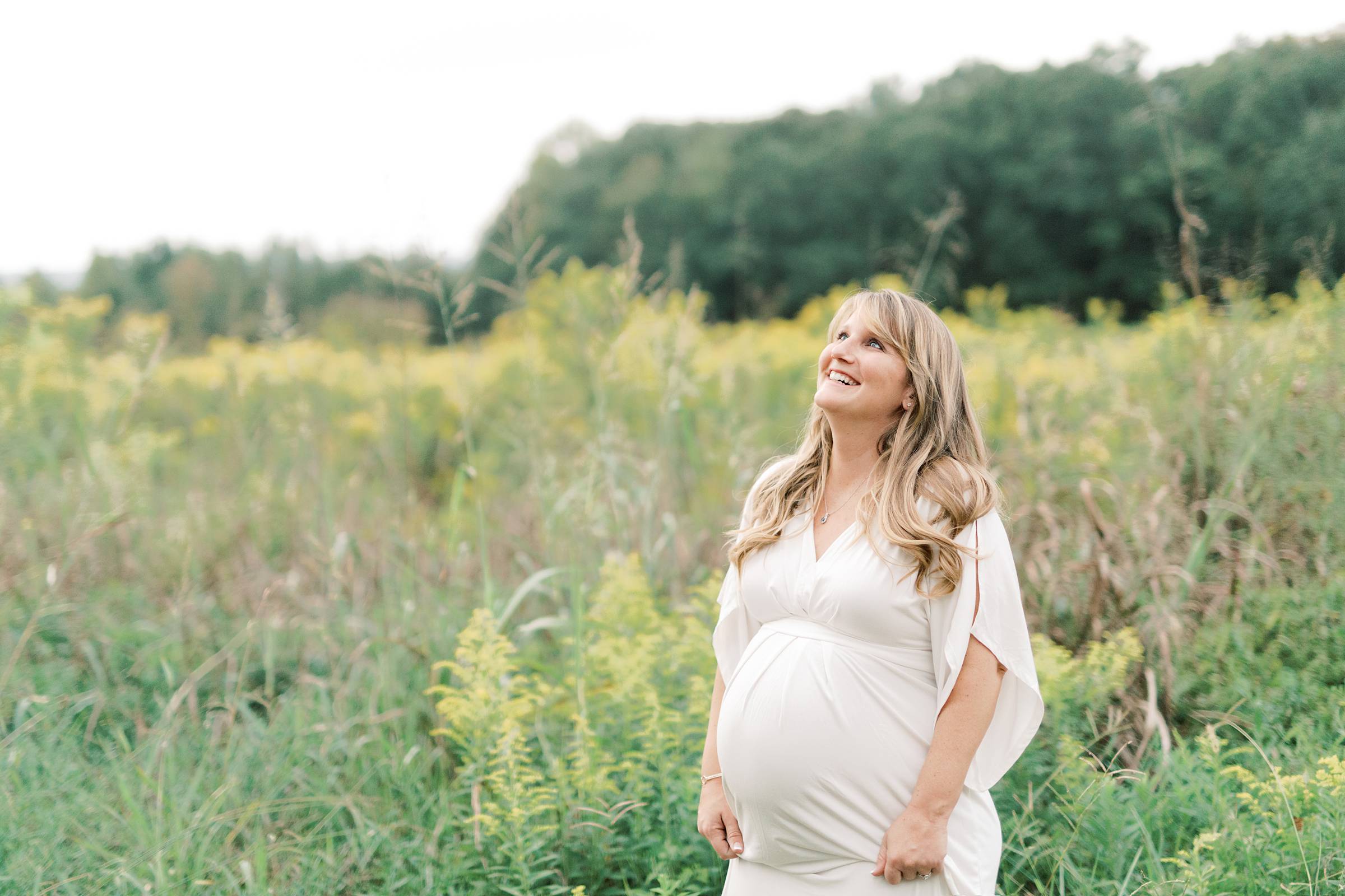 Pregnant woman in white dress in a field of wildflowers
